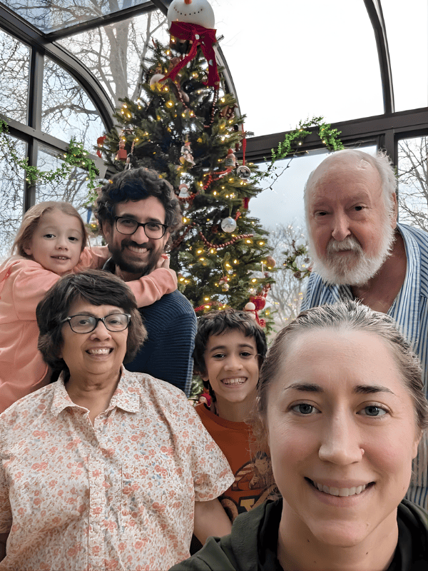 Multigenerational family posing together for a selfie in front of a decorated Christmas tree