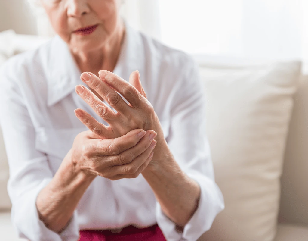 Close view of an older womans hands pressed together as she rubs her fingers and knuckles