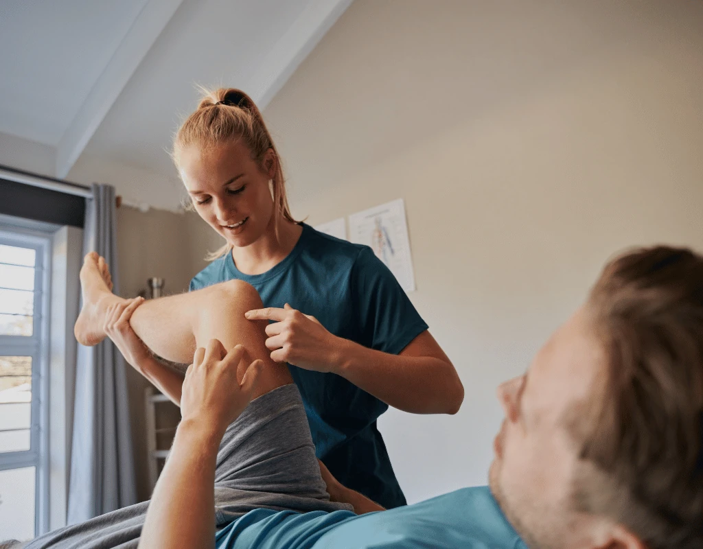 Therapist moving a patients arm and shoulder while she lies on a treatment table