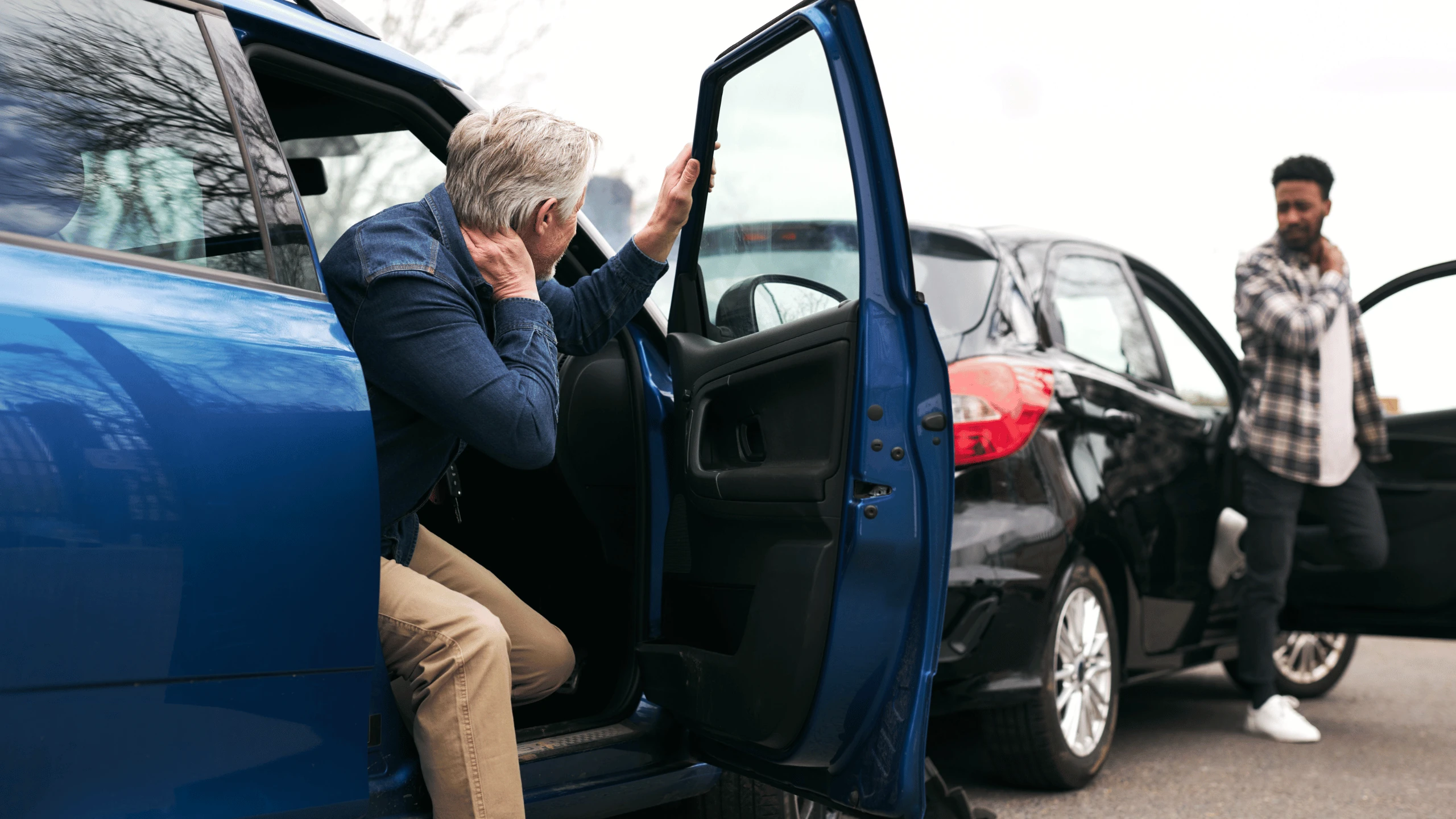 Older man stepping out of a blue vehicle while others unload belongings nearby