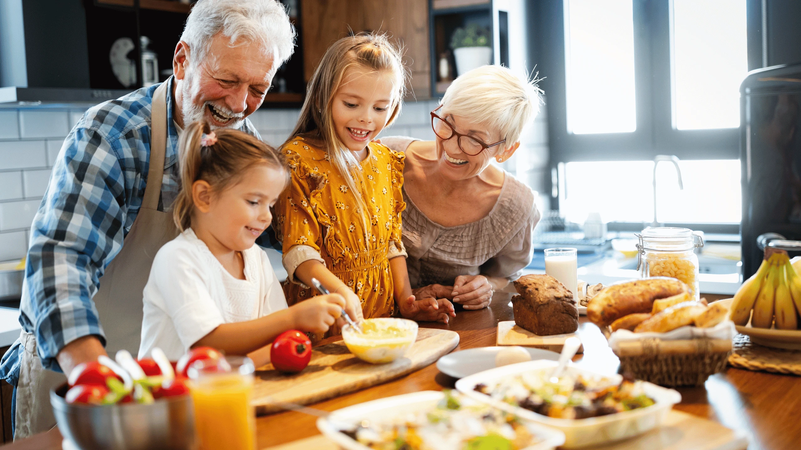 Grandparents, parents and children preparing fruit and food together around a kitchen island