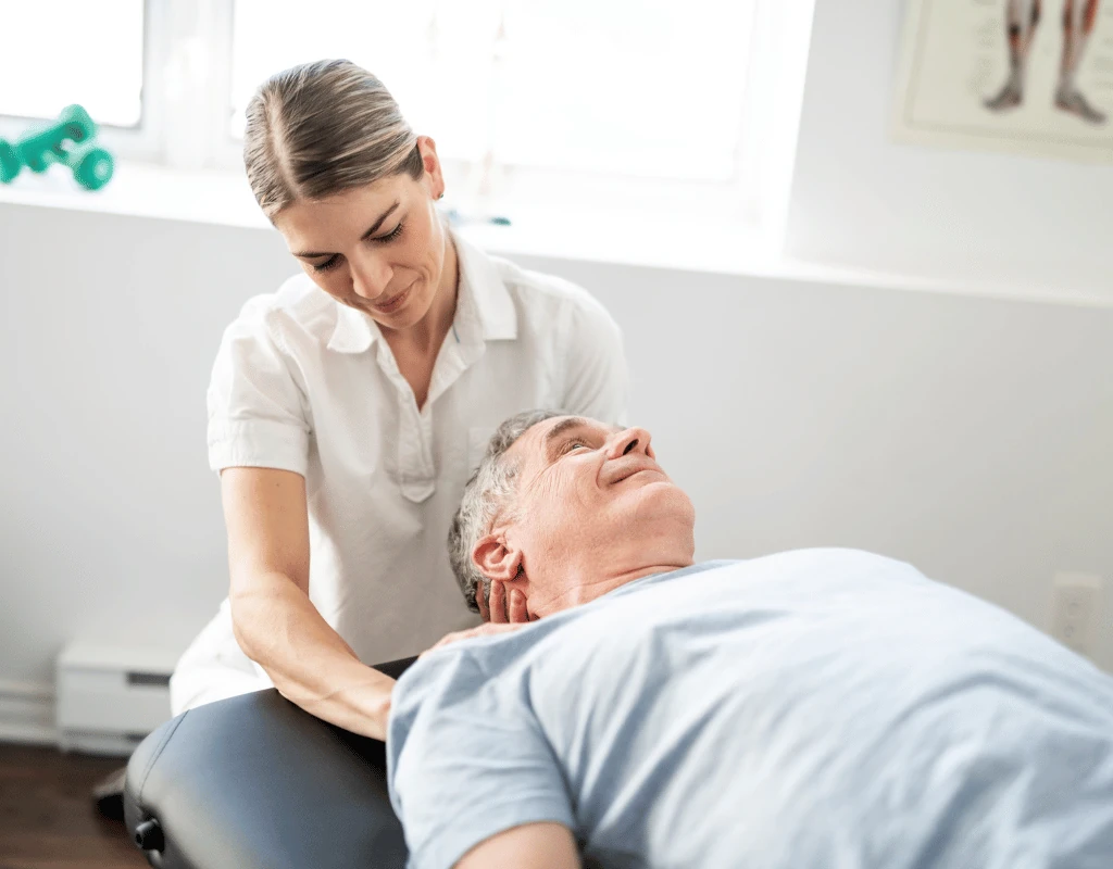 Therapist supporting an older mans head and neck while he lies on a treatment table