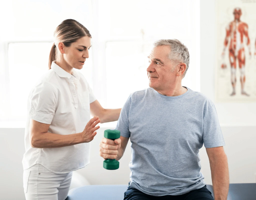 Therapist steadying an older mans shoulder while he holds a green dumbbell at his side