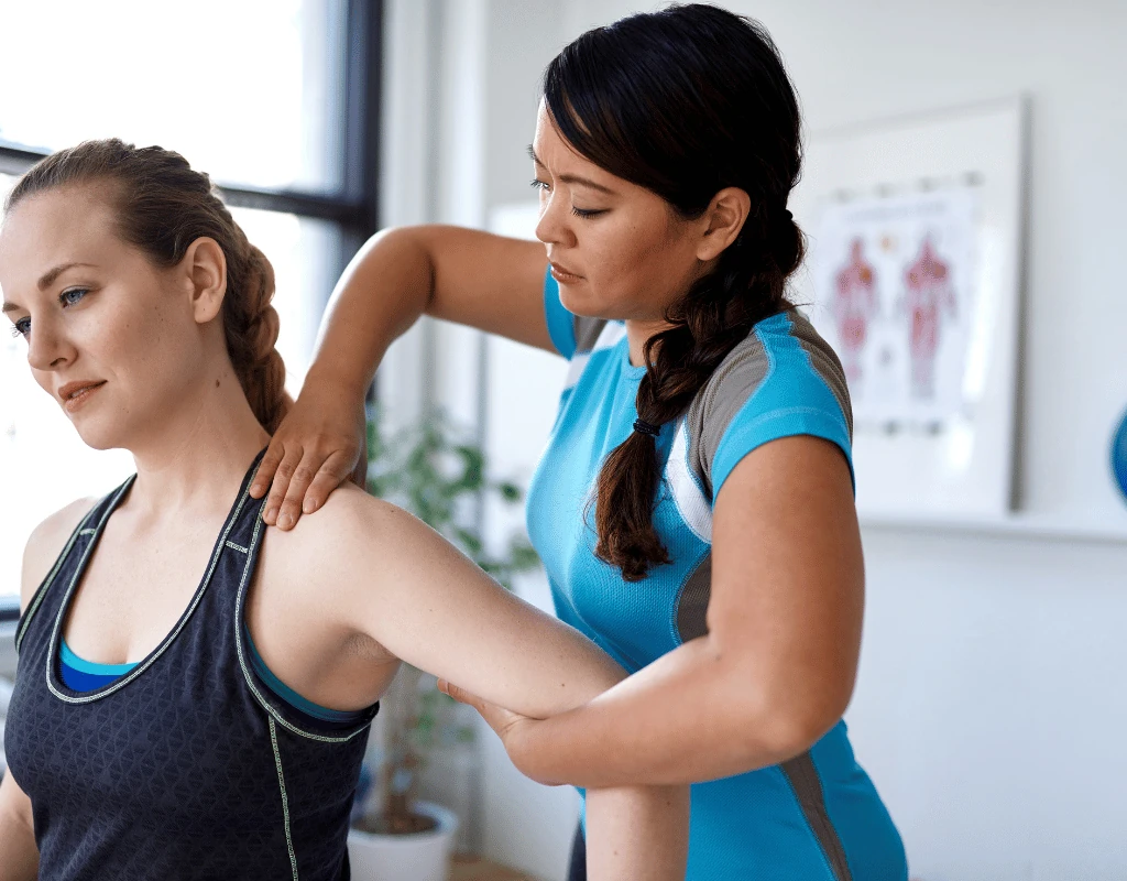 Therapist standing behind a woman assessing the position of both shoulders and upper back