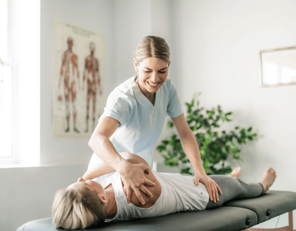 Therapist applying a hands-on technique to a womans abdomen and hip while she lies on her back