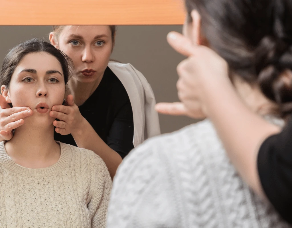 Speech therapist demonstrating mouth and lip movements while two clients copy the exercise