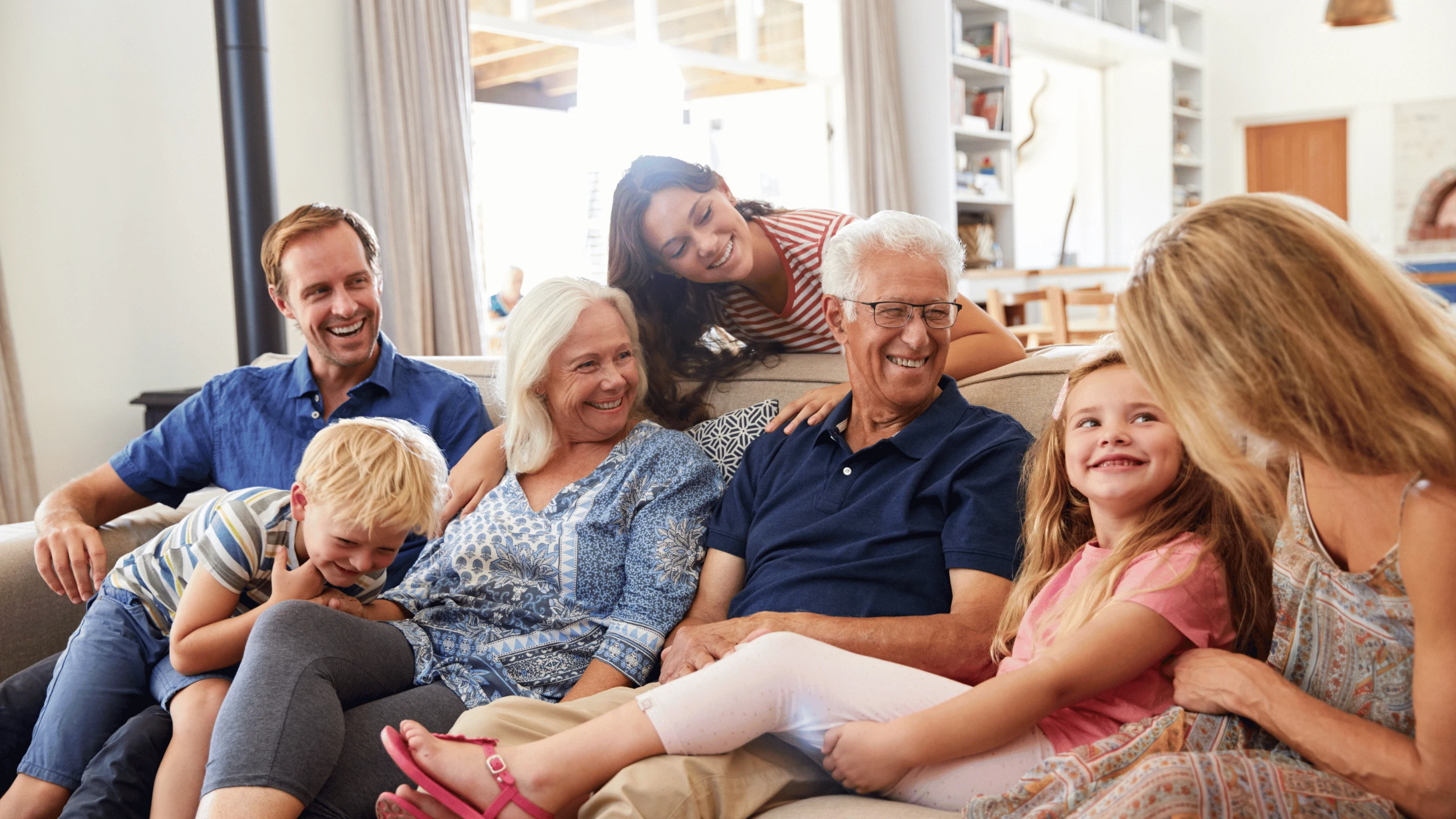 Three generations of a family sitting close together on a living room sofa