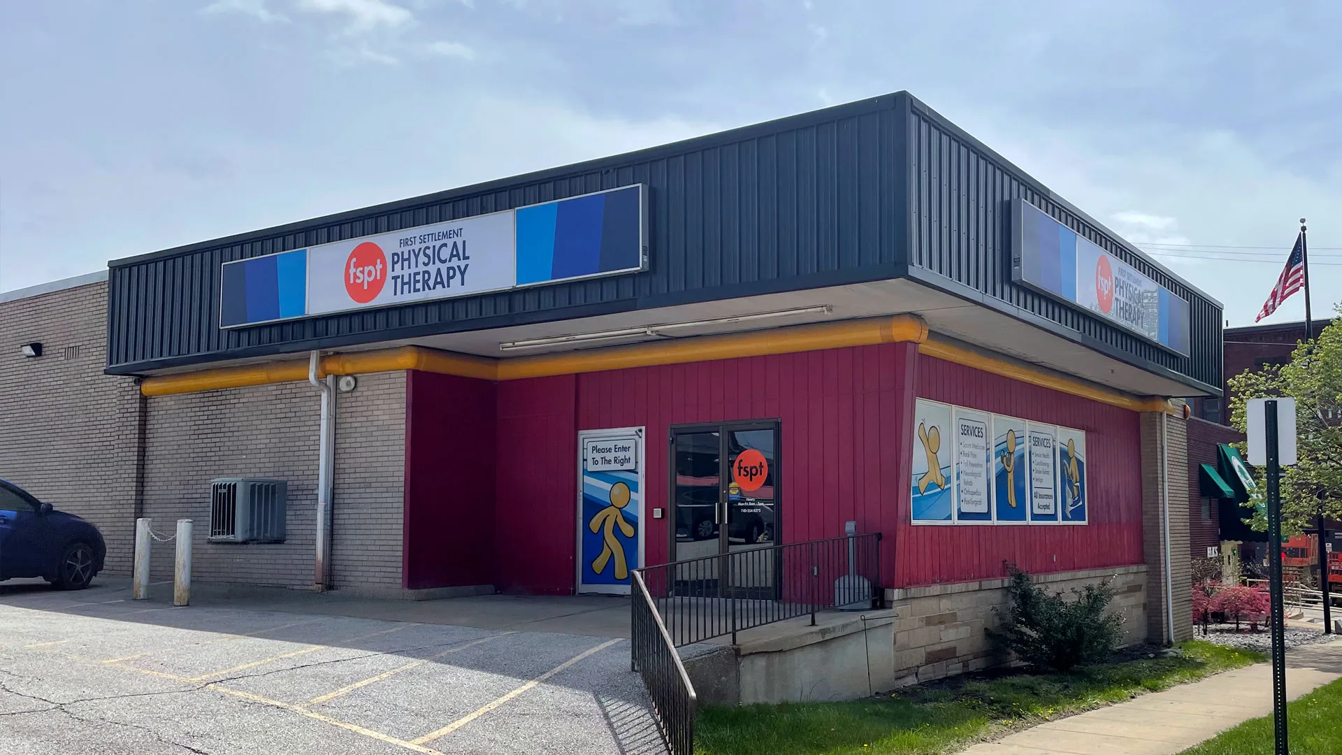 Building with red and dark blue cladding, a clinic sign above the entrance and an American flag flying beside it