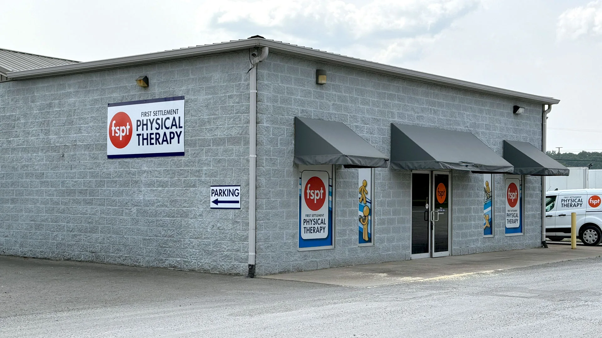 White block building with grey awnings over the windows and clinic signage beside the entrance