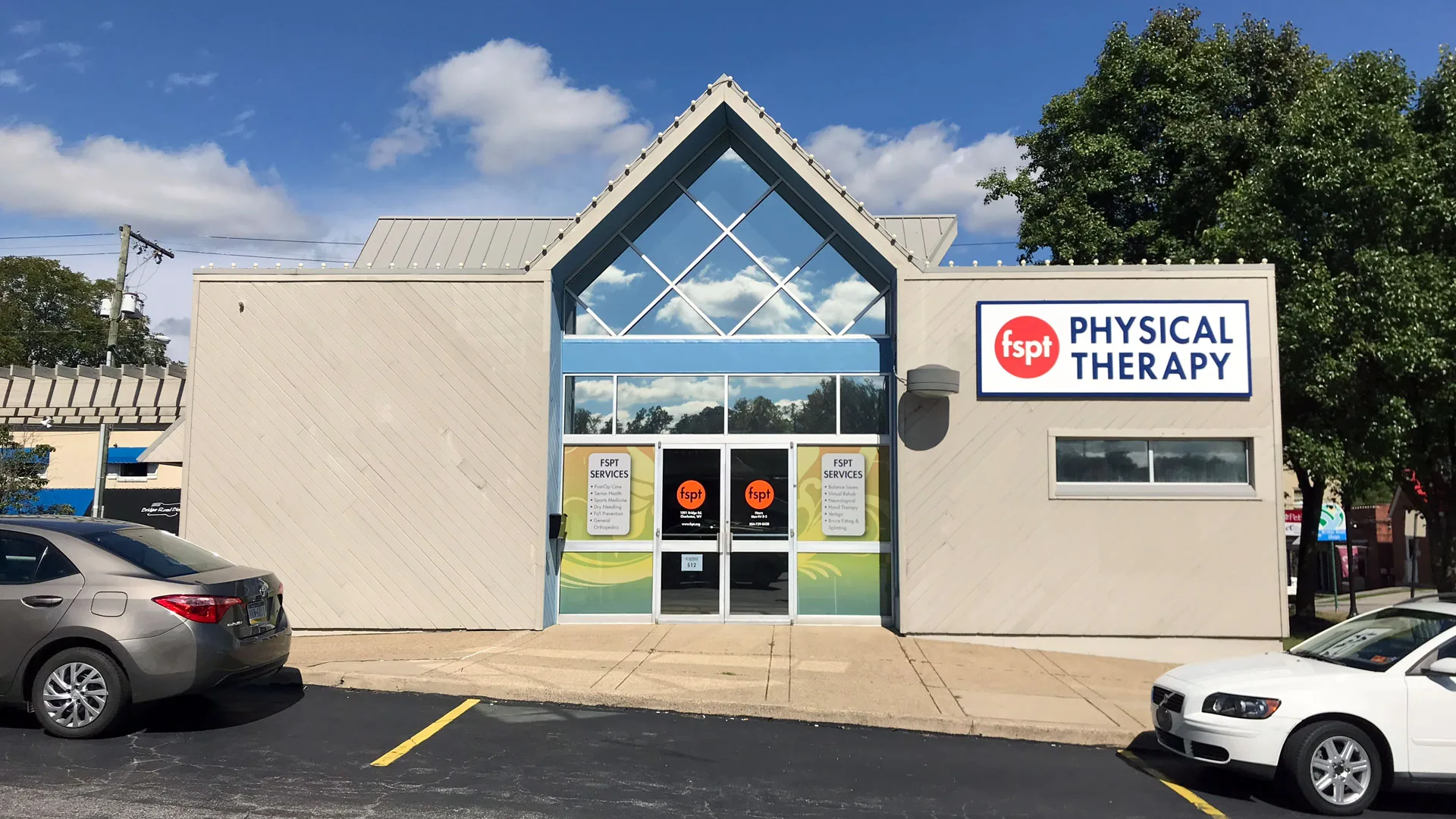 White building with a tall arched glass entryway and a Physical Therapy sign mounted beside it