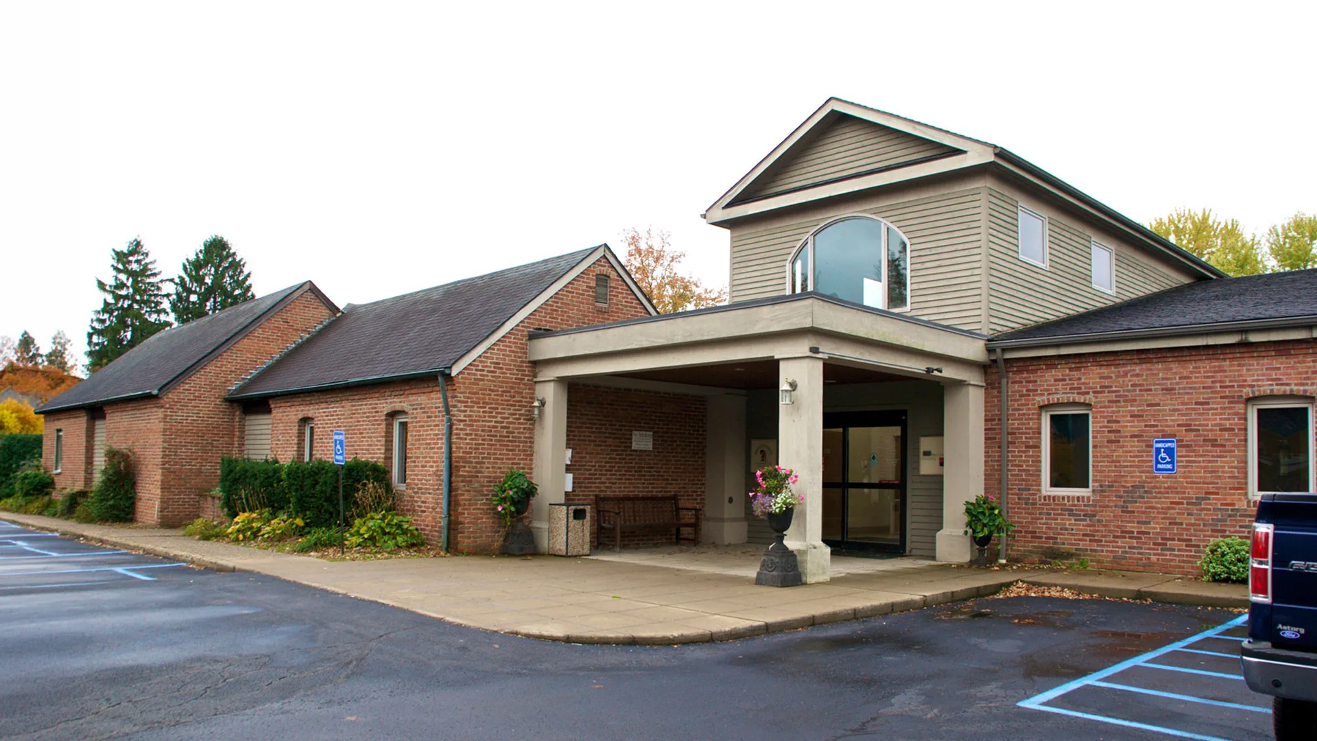 Brick professional building with a columned portico entrance and a paved parking lot in front