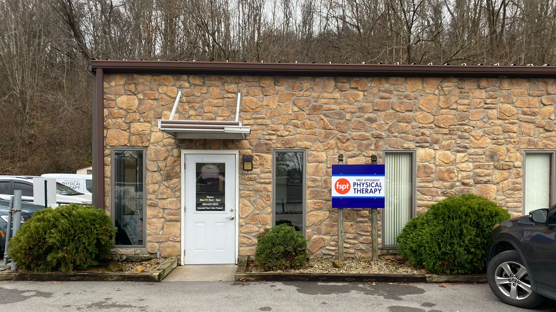 Stone-faced single-story building with a white entrance door and a small First Settlement Physical Therapy sign
