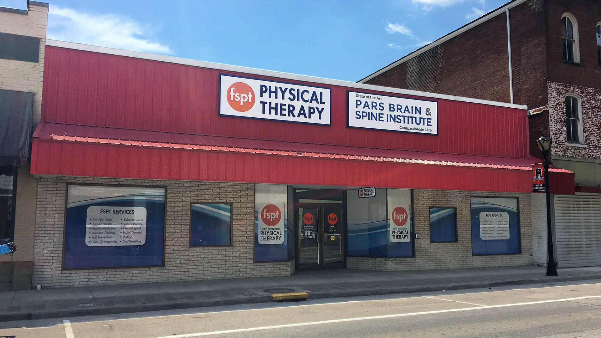 Building with a red upper facade housing the physical therapy clinic alongside a brain and spine institute office